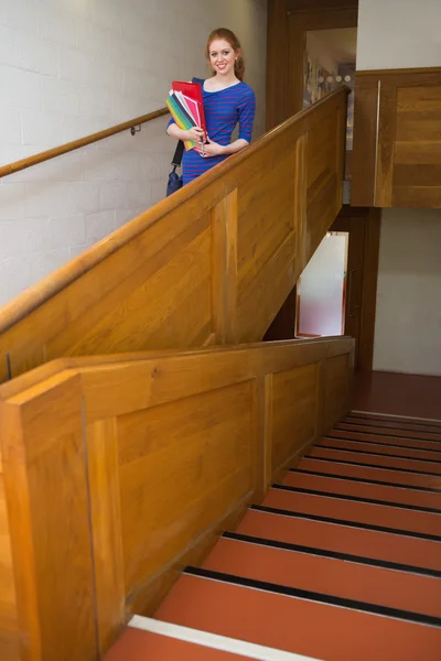 Happy student holding folders on the stairs looking at camera — Stock Photo, Image