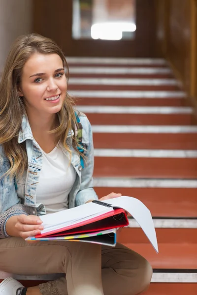 Cheerful young student sitting on stairs looking at camera — Stock Photo, Image