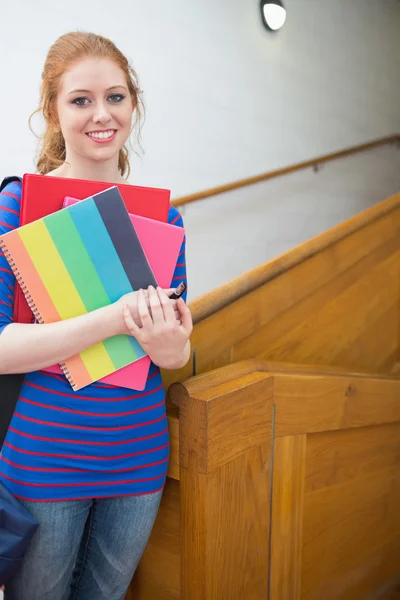 Pretty student standing on the stairs smiling at camera — Stock Photo, Image