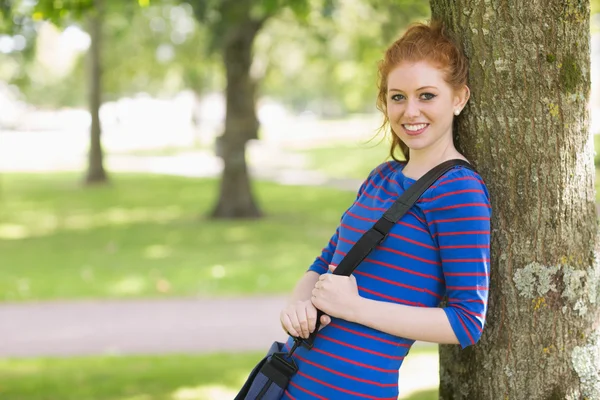 Niedliche rothaarige Studentin lehnt an einem Baum — Stockfoto