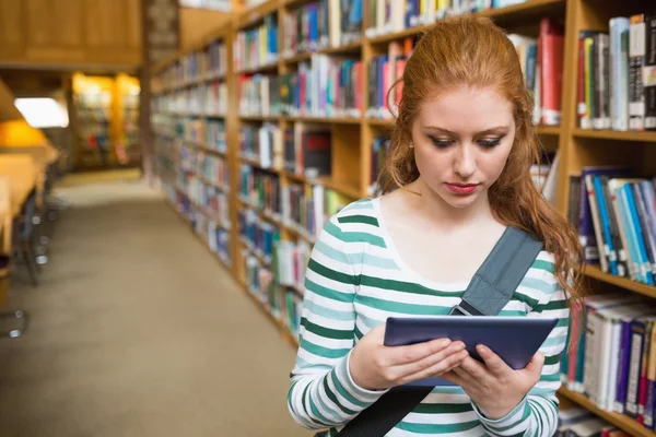 Poważnego studenta za pomocą tabletu stojący w bibliotece — Zdjęcie stockowe