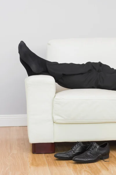 Låga delen av affärsmannen vila på soffan i vardagsrummet — Stockfoto