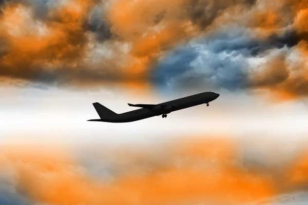 Flugzeug fliegt über orangefarbenen Himmel — Stockfoto