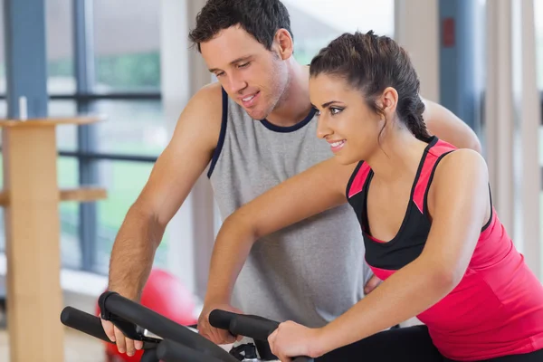 Entrenador ayudando a la mujer a hacer ejercicio en la clase de spinning — Foto de Stock