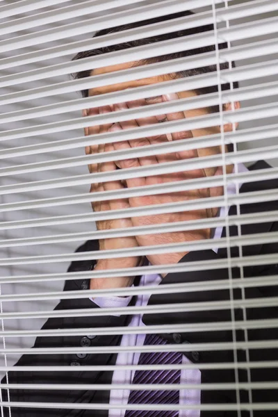 Businessman with head in hands in front of blinds in office — Stock Photo, Image