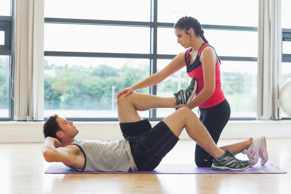 Kvinnliga tränare tittar på mannen göra buk crunches — Stockfoto