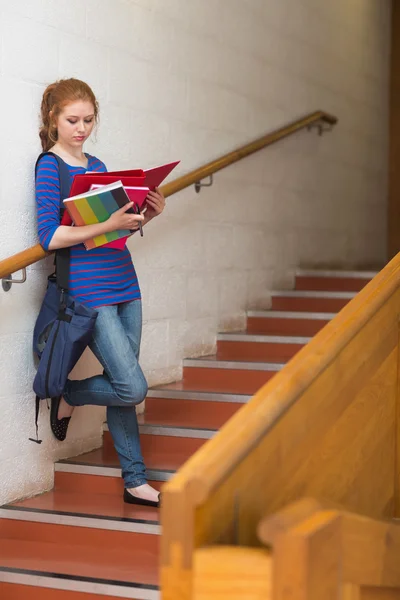 Kızıl saçlı ciddi öğrenci okuma notları merdivenlerde — Stok fotoğraf