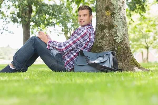 Usměvavý student pomocí jeho tablet studovat mimo — Stock fotografie