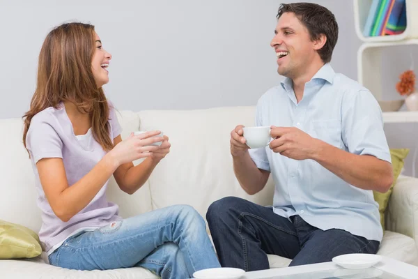 Linda pareja sentada en el sofá con tazas de té en casa — Foto de Stock