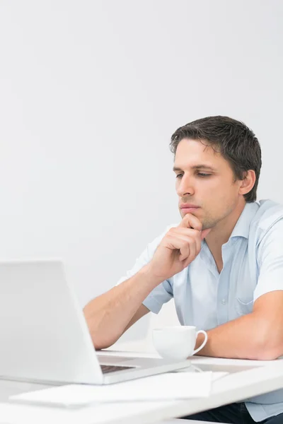 Vista lateral de un hombre serio usando el ordenador portátil en casa — Foto de Stock