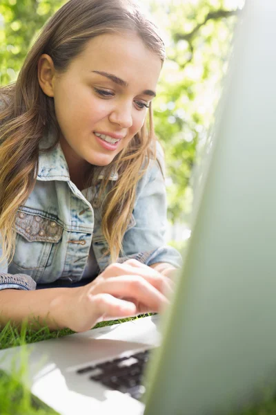 Young student lying on the grass using her laptop — Stock Photo, Image