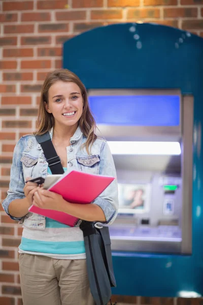 Hezká student postavení se usmívá na kameru na atm — Stock fotografie