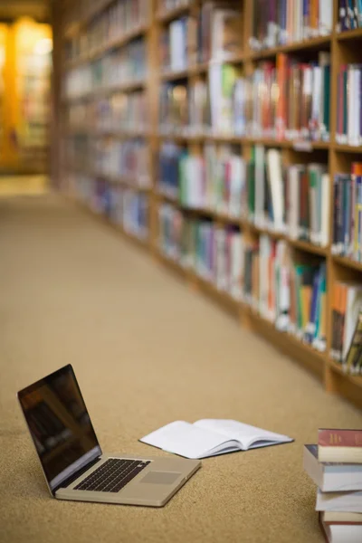 Laptop och böcker på golvet i biblioteket — Stockfoto