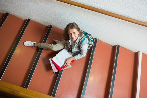 Leende ung student sitter på trappan tittar upp på kameran — Stockfoto