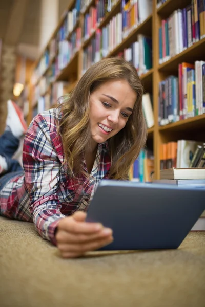 Young student lying on library floor using tablet Stock Picture