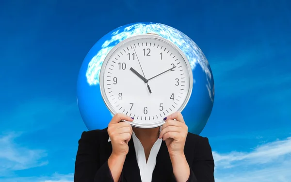 Composite image of businesswoman in suit holding a clock — Stock Photo, Image