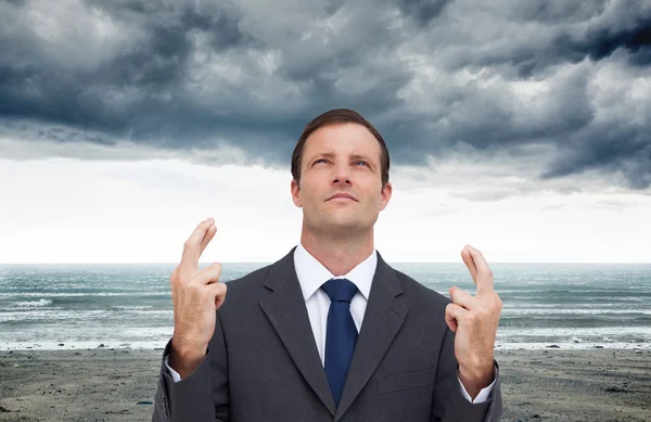 Businessman with fingers crossed is looking up — Stock Photo, Image