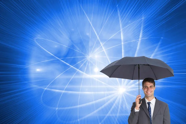 Imagen compuesta de un empresario feliz sosteniendo un paraguas gris — Foto de Stock