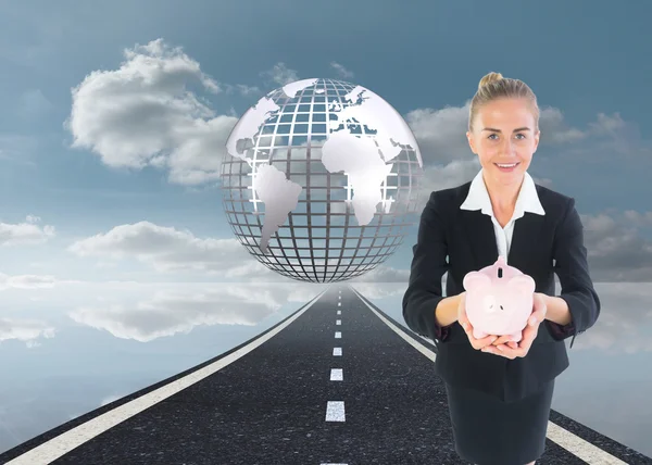 Composite image of businesswoman holding pink piggy bank — Stock Photo, Image