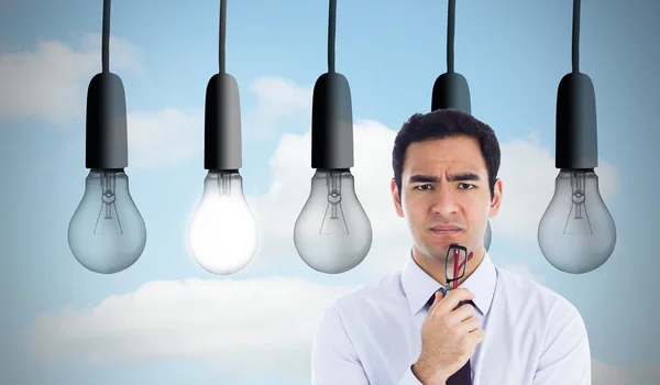 Composite image of thinking businessman holding glasses — Stock Photo, Image