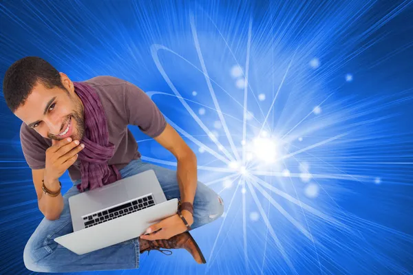 Composite image of thoughtful man sitting on floor using laptop — Stock Photo, Image