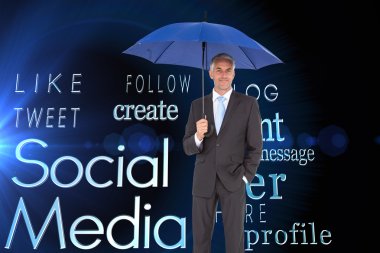 Businessman smiling at camera and holding blue umbrella clipart