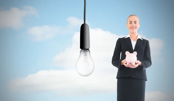 Composite image of businesswoman holding pink piggy bank — Stock Photo, Image