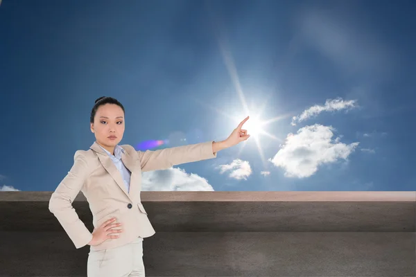 Composite image of unsmiling asian businesswoman pointing — Stock Photo, Image