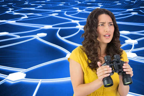 Composite image of serious casual young woman holding binoculars — Stock Photo, Image