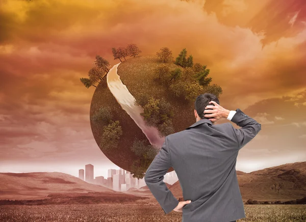 Composite image of young businessman standing back to camera scratching his head — Stock Photo, Image