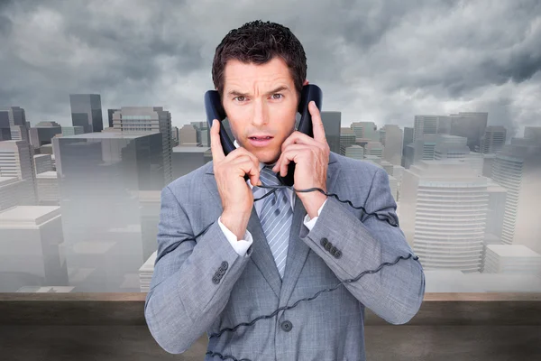 Angry businessman tangle up in phone wires — Stock Photo, Image