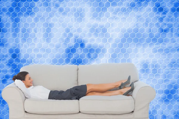 Composite image of smiling business woman lying down on the couc — Stock Photo, Image