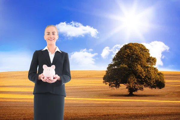 Composite image of businesswoman holding pink piggy bank — Stock Photo, Image