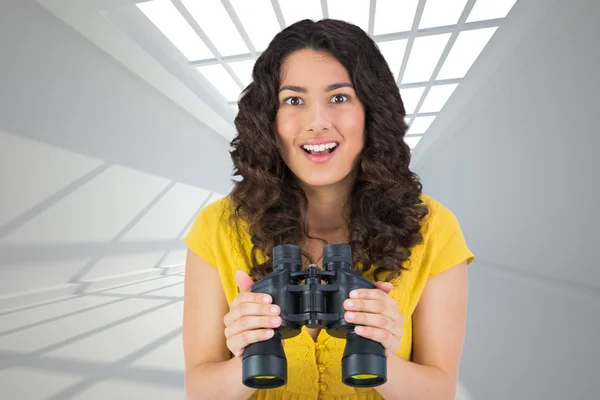Composite image of smiling casual young woman holding binoculars — Stock Photo, Image
