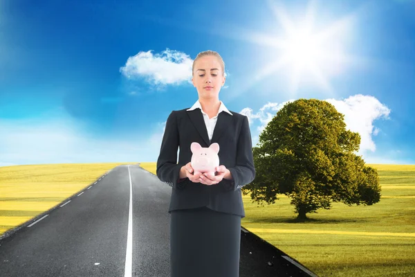 Composite image of businesswoman holding pink piggy bank — Stock Photo, Image