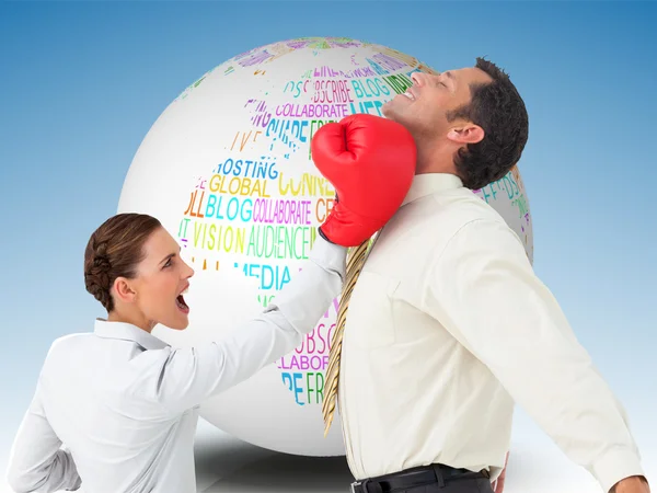 Businesswoman hitting a businessman with boxing gloves — Stock Photo, Image