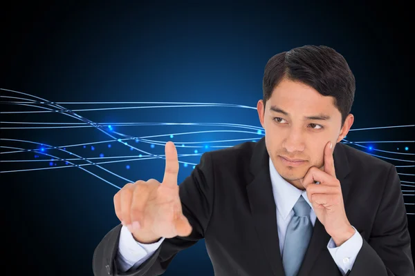 Composite image of thoughtful asian businessman pointing — Stock Photo, Image