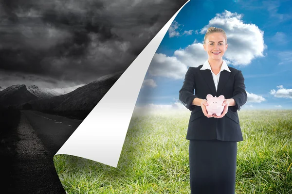 Composite image of happy businesswoman holding a piggy bank — Stock Photo, Image