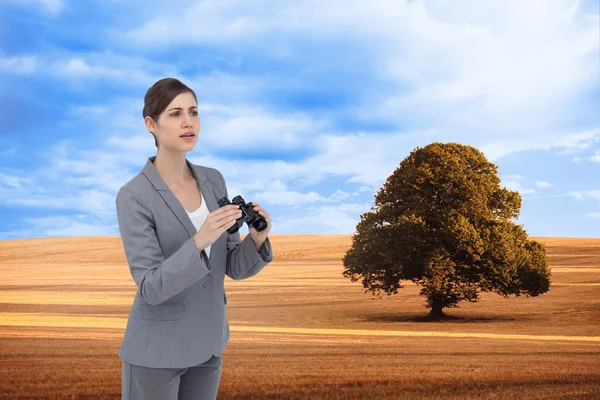 Composite image of curious young businesswoman with binoculars — Stock Photo, Image