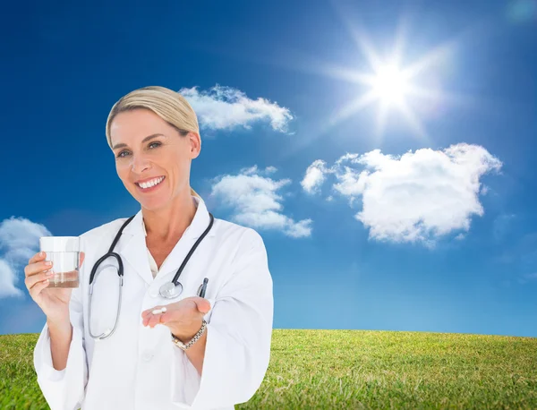 Happy doctor holding out pills and water glass — Stock Photo, Image