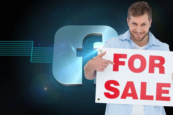Smiling model holding a for sale sign — Stock Photo, Image