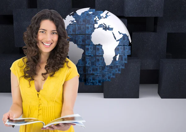 Composite image of cheerful curly haired brunette reading magazine — Stock Photo, Image