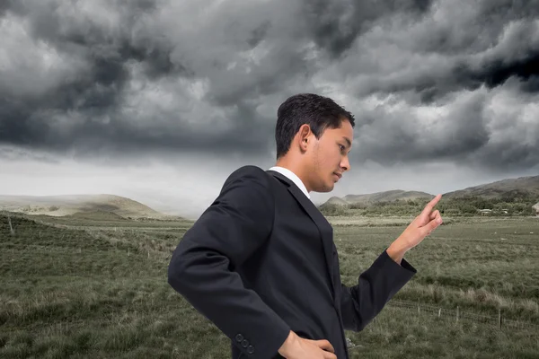 Composite image of unsmiling asian businessman pointing — Stock Photo, Image