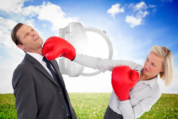 Businesswoman hitting colleague with her boxing gloves — Stock Photo, Image