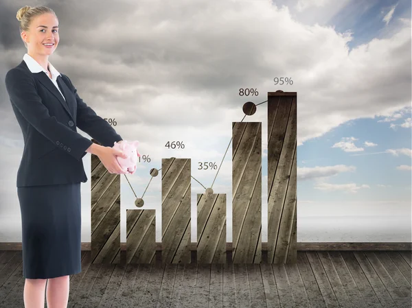 Composite image of businesswoman holding pink piggy bank — Stock Photo, Image