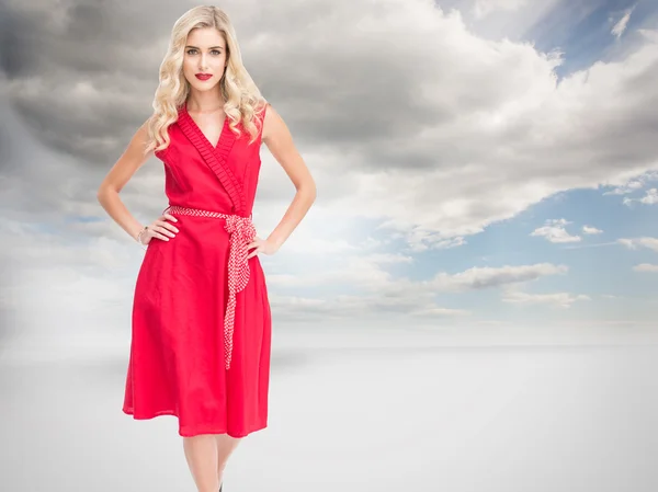 Blondynka stoi ręce na biodra w czerwonej sukience — Zdjęcie stockowe