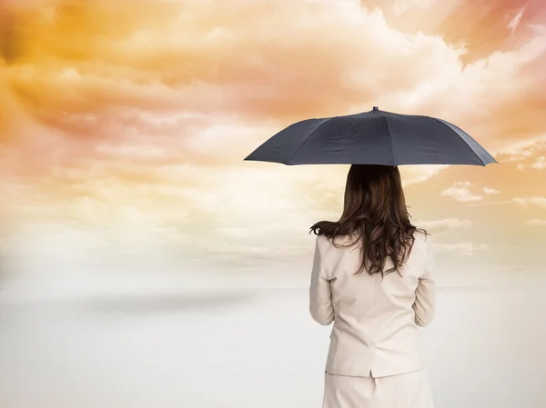Imagen compuesta de la vista trasera de la elegante mujer de negocios que sostiene el paraguas — Foto de Stock