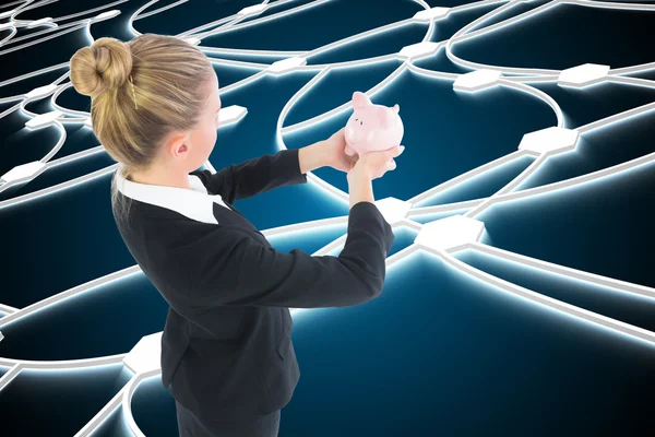 Composite image of businesswoman holding pink piggy bank — Stock Photo, Image