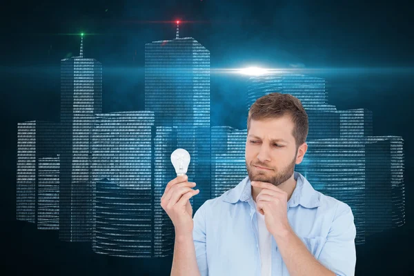 Composite image of sceptical model holding a bulb — Stock Photo, Image