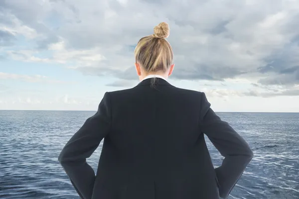 Composite image of businesswoman standing with hands on hips — Stock Photo, Image